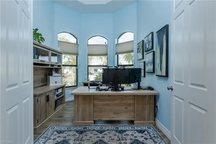 Office with wood finished floors and a high ceiling