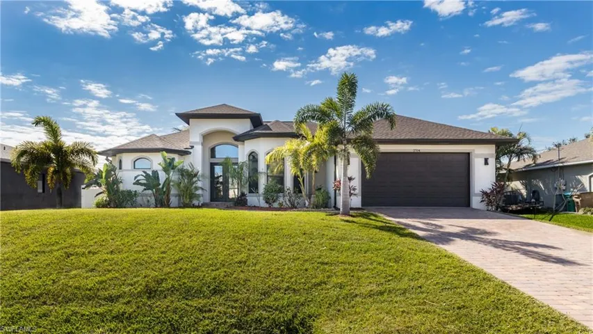 Mediterranean / spanish home featuring stucco siding, decorative driveway, a front lawn, a garage, and roof with shingles
