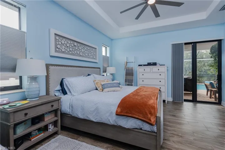 Bedroom with access to outside, wood finished floors, ceiling fan, and a raised ceiling