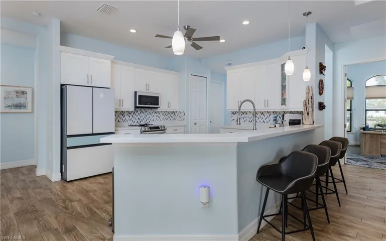 Kitchen featuring freestanding refrigerator, light wood-style floors, ceiling fan, and tasteful backsplash