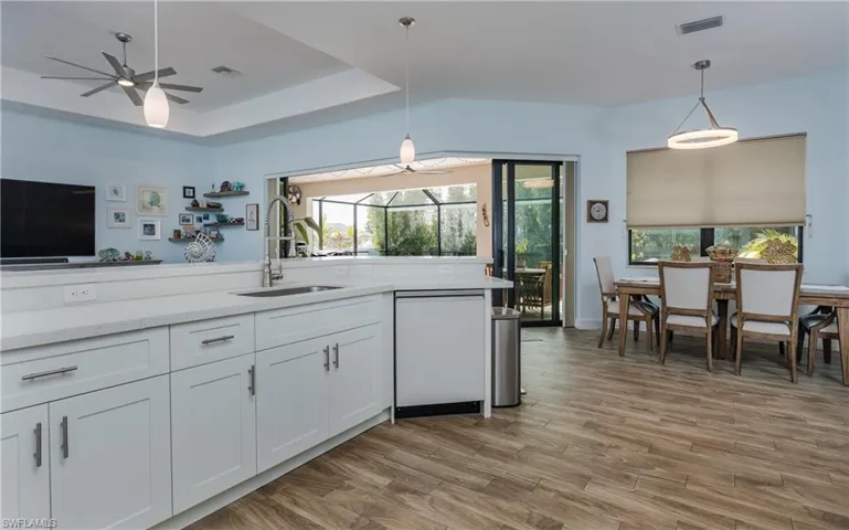 Kitchen with white cabinetry, dishwasher, a ceiling fan, light stone counters, and pendant lighting
