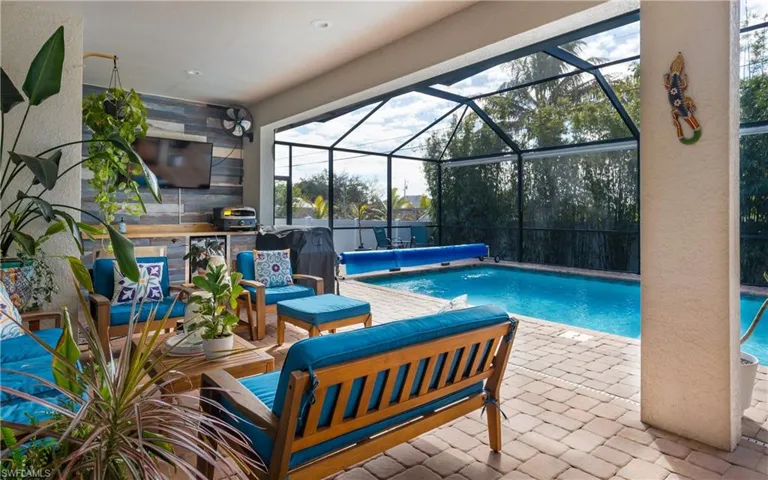 Swimming pool featuring a patio, glass enclosure, a sunroom, and an outdoor kitchen and area to lounge