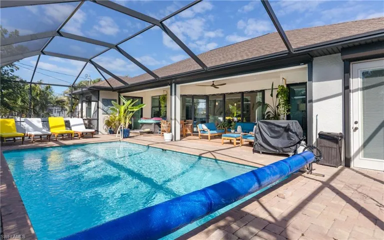 View of swimming pool featuring a covered pool, patio surround, a sunroom, grilling area, and glass enclosure