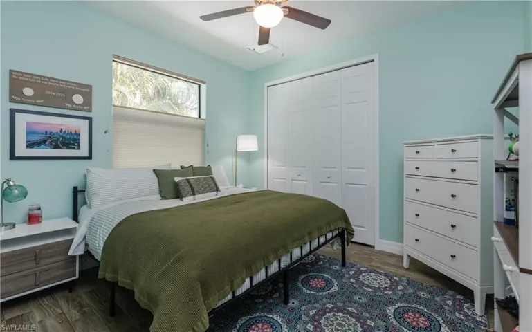 Bedroom with dark wood-type flooring, a closet, and a ceiling fan