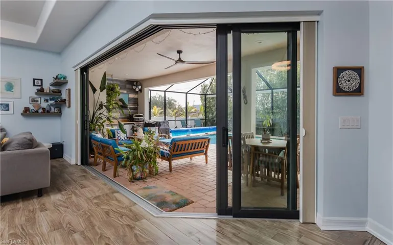 Doorway to outside with a sunroom, wood finished floors, and ceiling fan