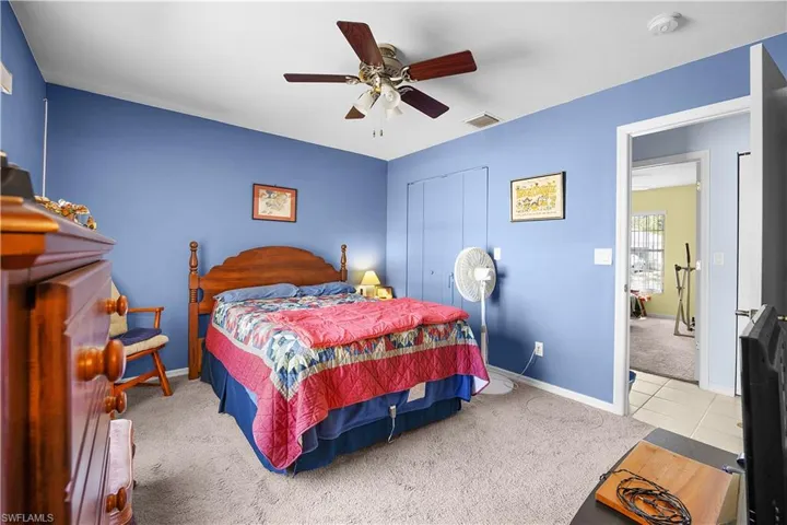 Bedroom with light carpet, ceiling fan, and a closet