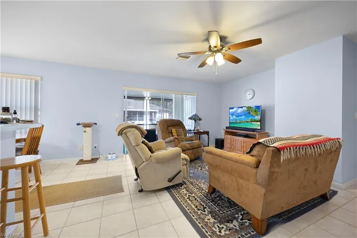 Living room with a ceiling fan and light tile patterned floors