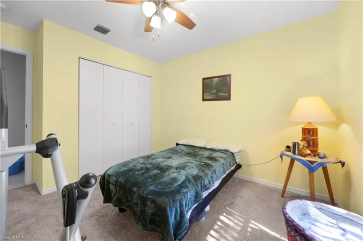 Carpeted bedroom with ceiling fan and a closet