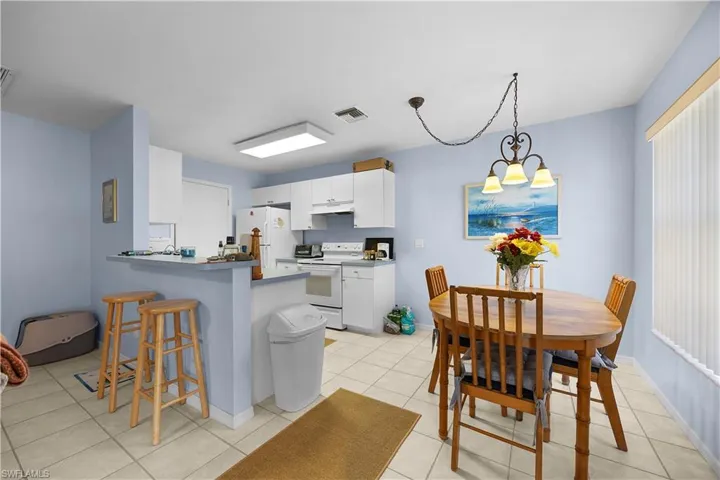Kitchen featuring white cabinetry, white appliances, a breakfast bar, a peninsula, and a chandelier