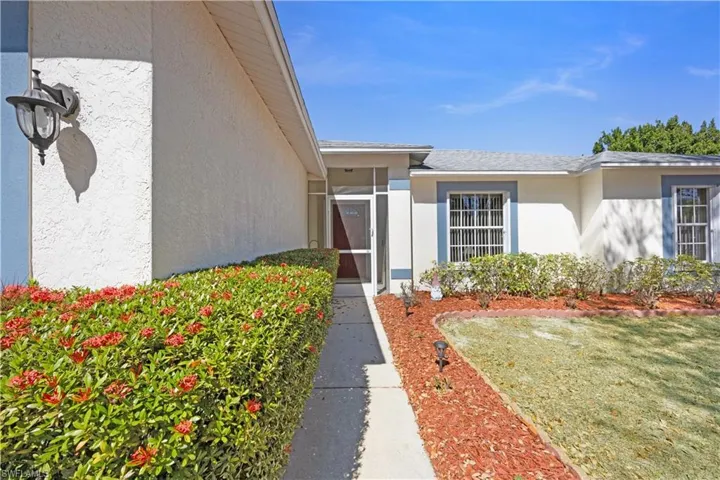 View of exterior entry featuring stucco siding, a yard, and a sunroom