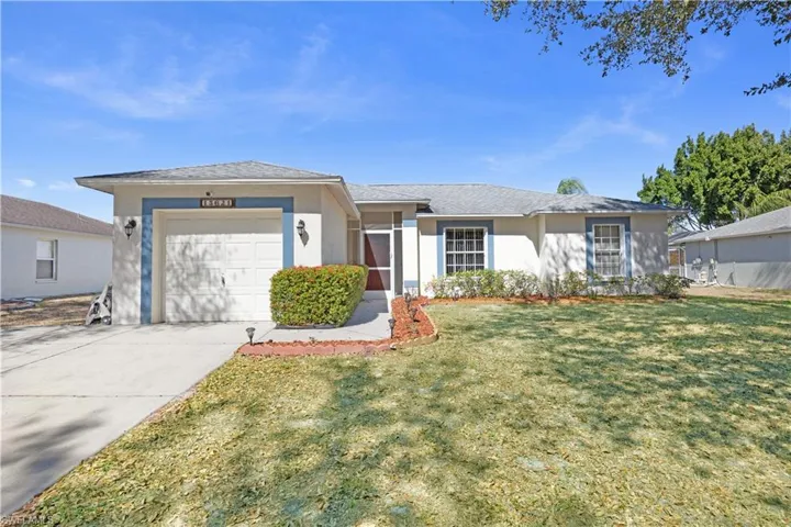Ranch-style house featuring stucco siding, an attached garage, a front yard, and concrete driveway