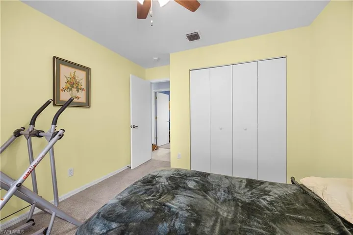 Bedroom with light colored carpet, ceiling fan, and a closet