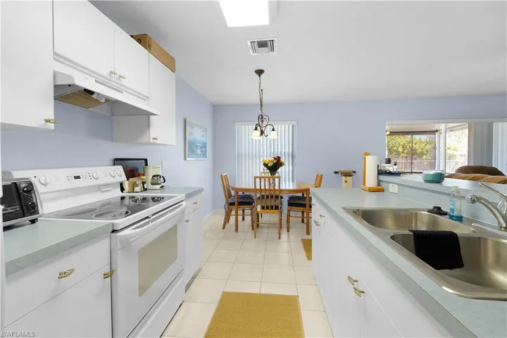 Kitchen with white cabinetry, white electric range oven, light countertops, and healthy amount of natural light