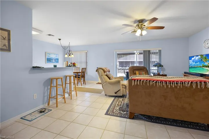 Living area featuring light tile patterned floors, ceiling fan, and suspended lighting
