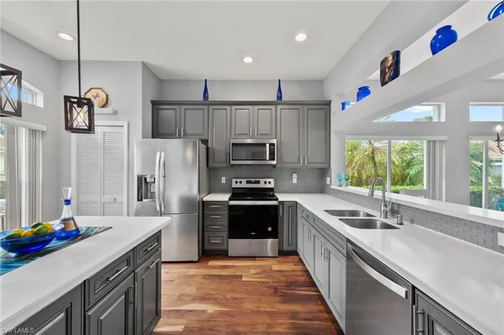 Kitchen with dark hardwood / wood-style flooring, stainless steel appliances, sink, and gray cabinetry