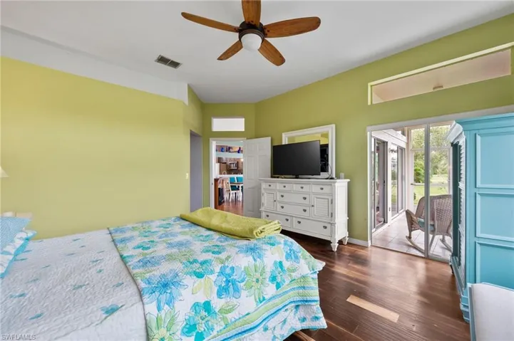 Bedroom featuring dark hardwood / wood-style floors, access to exterior, and ceiling fan