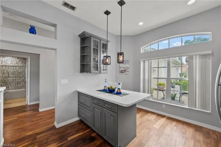 Kitchen with a wealth of natural light, gray cabinetry, and dark hardwood / wood-style flooring