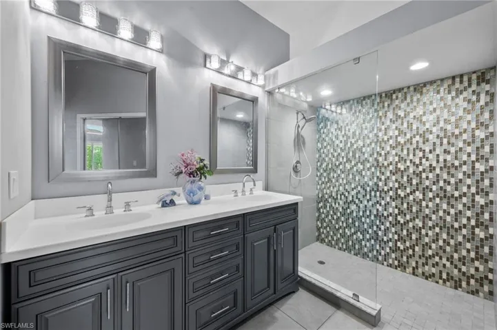 Bathroom featuring a tile shower, tile patterned floors, and vanity