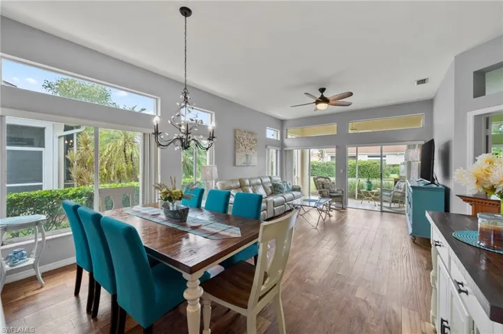 Dining room with plenty of natural light, ceiling fan with notable chandelier, and hardwood / wood-style floors