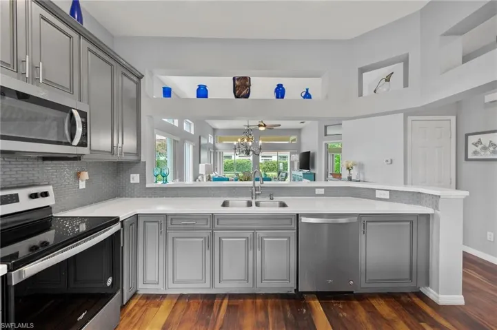Kitchen with dark wood-type flooring, stainless steel appliances, sink, and kitchen peninsula