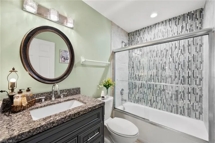 Full bathroom with vanity, enclosed tub / shower combo, and toilet