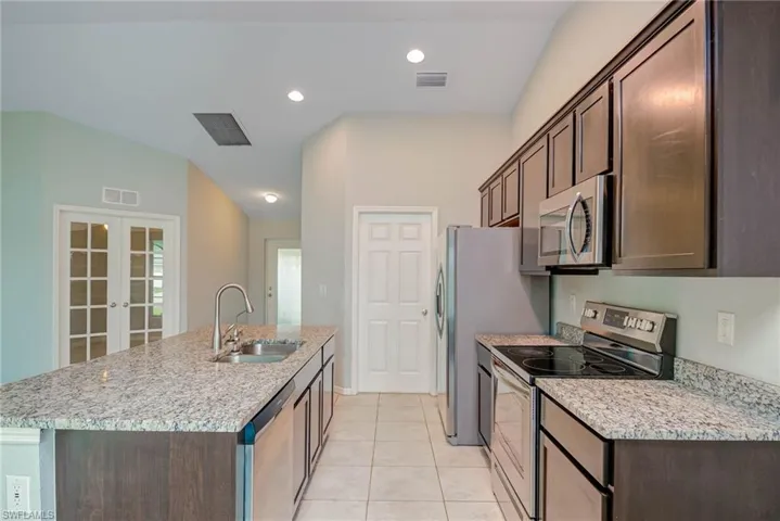 Kitchen featuring visible vents, a sink, stainless steel appliances, dark brown cabinetry, and french doors