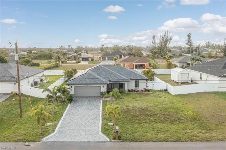 View of front facade with a front lawn, a residential view, decorative driveway, a fenced backyard, and an attached garage
