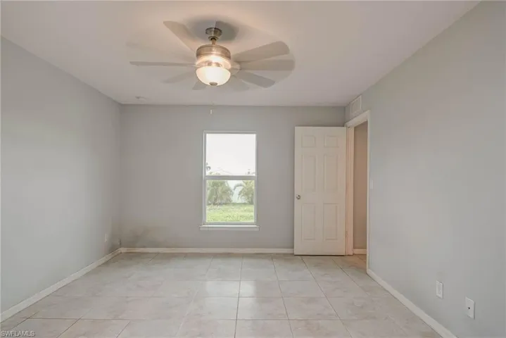 Unfurnished room featuring light tile patterned floors, visible vents, ceiling fan, and baseboards