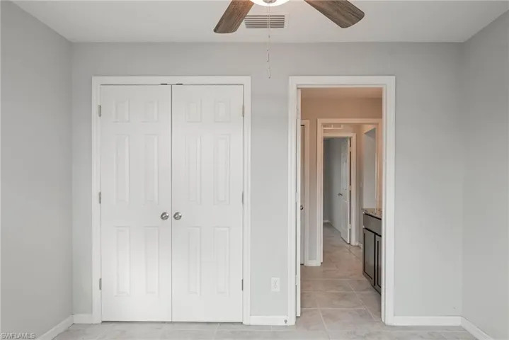 Unfurnished bedroom featuring visible vents, ceiling fan, baseboards, light tile patterned flooring, and a closet