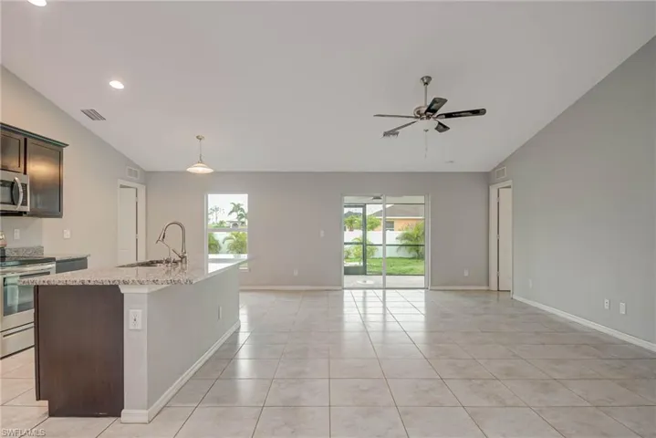 Kitchen with light tile patterned floors, vaulted ceiling, stainless steel appliances, and a sink