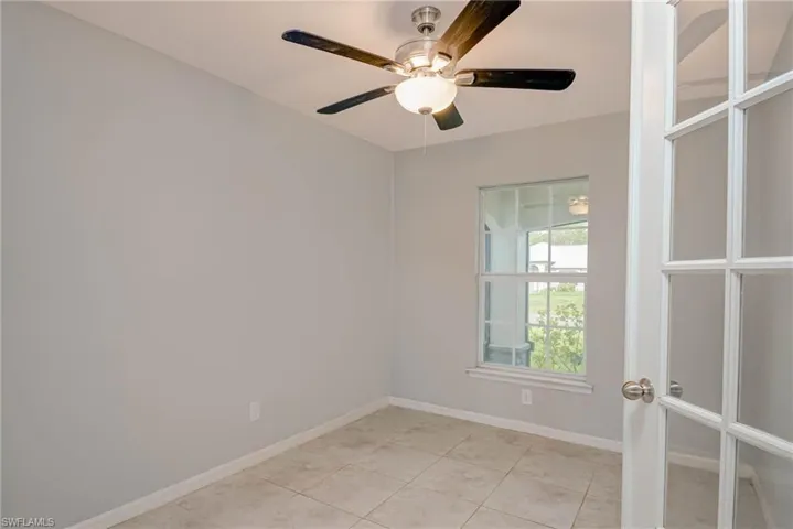 Empty room with light tile patterned floors, ceiling fan, french doors, and baseboards