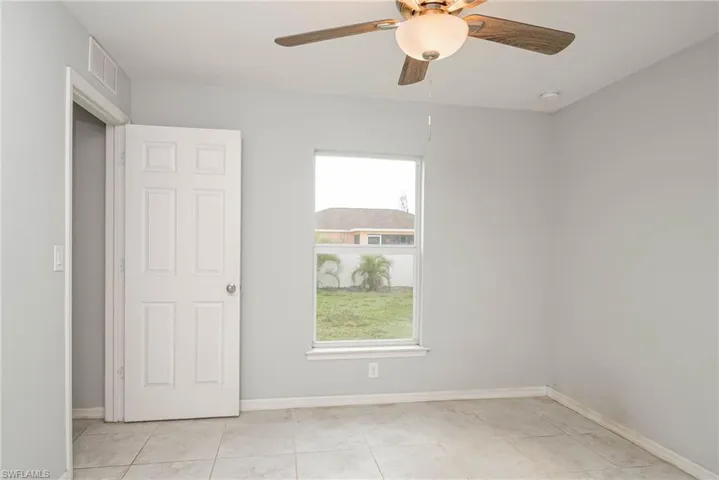 Empty room with light tile patterned floors, baseboards, and visible vents