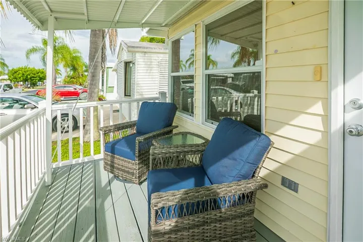 Covered porch with light-colored siding, white railings, and a light-toned flooring