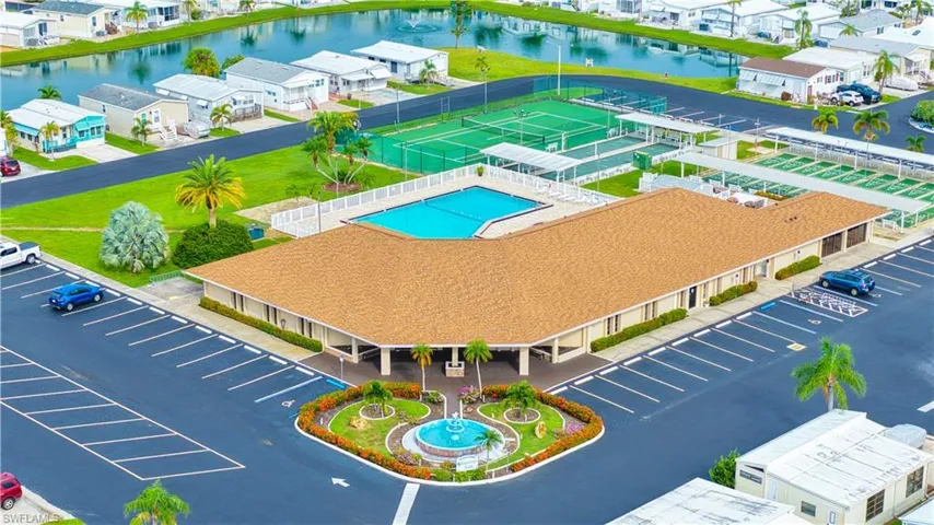 Expansive property featuring a large parking area, central building with a shingle roof, swimming pool, tennis courts, and bocce ball courts