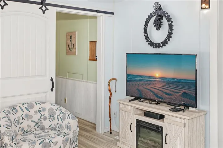Sliding barn door with black hardware, wood-finish flooring, and white paneled walls