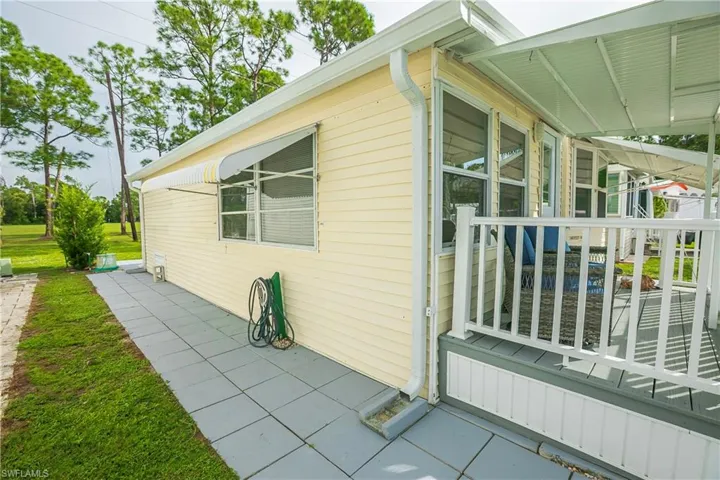 Exterior featuring horizontal siding, multiple windows, a covered porch with white railing, and a paved walkway