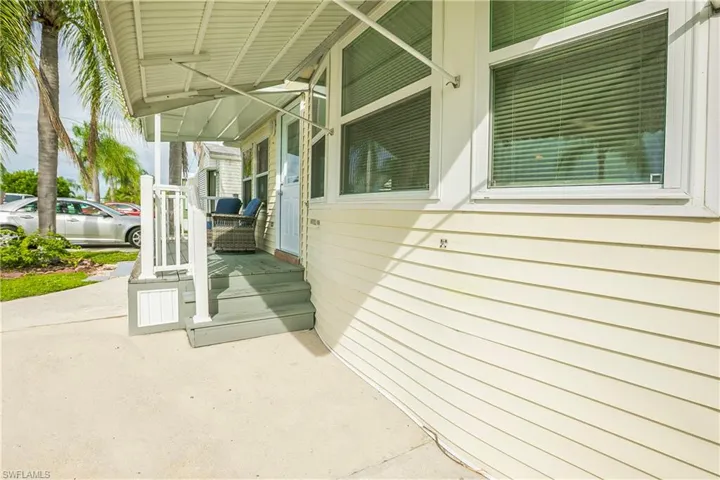 Entry porch with steps, white railing, and an awning