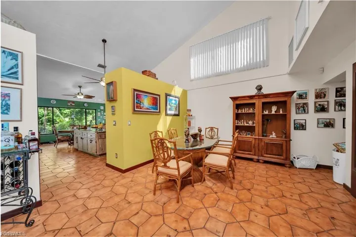 Vaulted ceiling with high windows, geometric tile flooring, built-in wooden display cabinet, and a partial wall feature