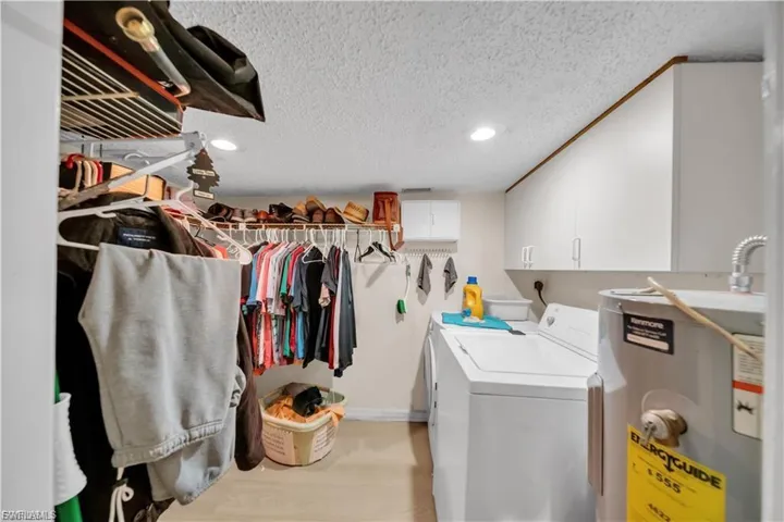 Recessed lighting, wall-mounted storage cabinetry, built-in shelving, and light-toned flooring