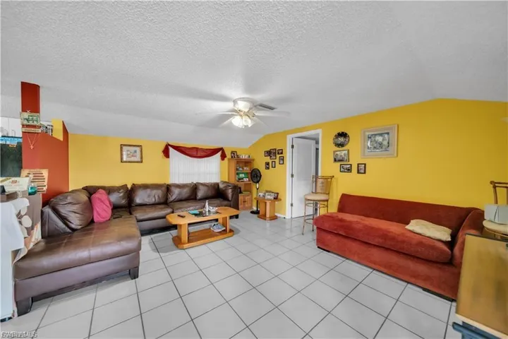 Tiled flooring throughout, sloped ceiling, and ceiling fan with light fixture