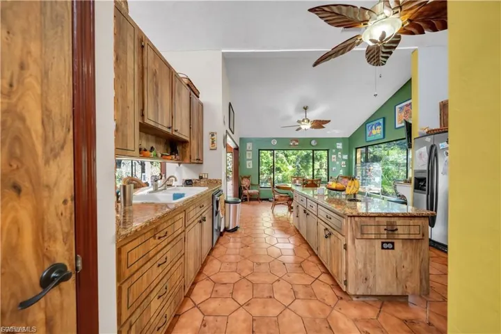 Kitchen featuring wood cabinetry, an elongated island with an integrated sink, and an open layout