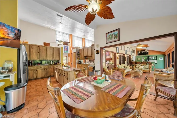 Vaulted ceiling, open concept design, wood-finish cabinetry, tile flooring, and a kitchen island with seating