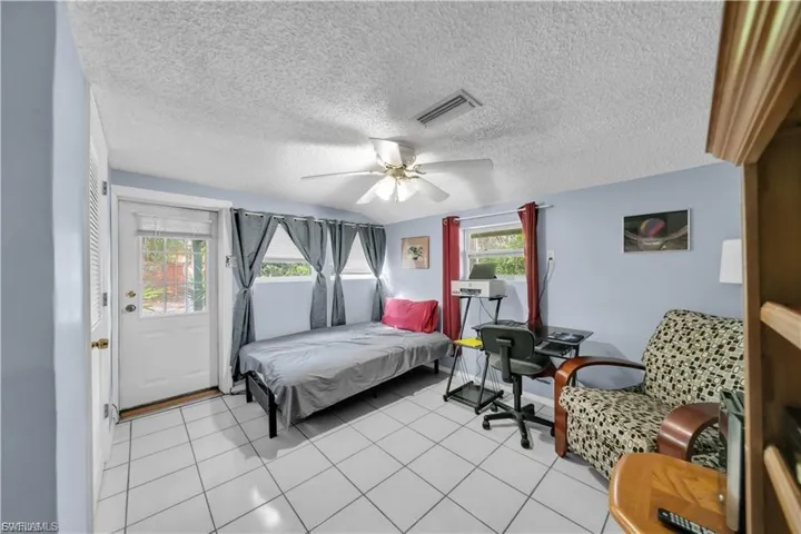 Light blue painted walls, white tile flooring, ceiling fan with light, and a white exterior door with glass insert