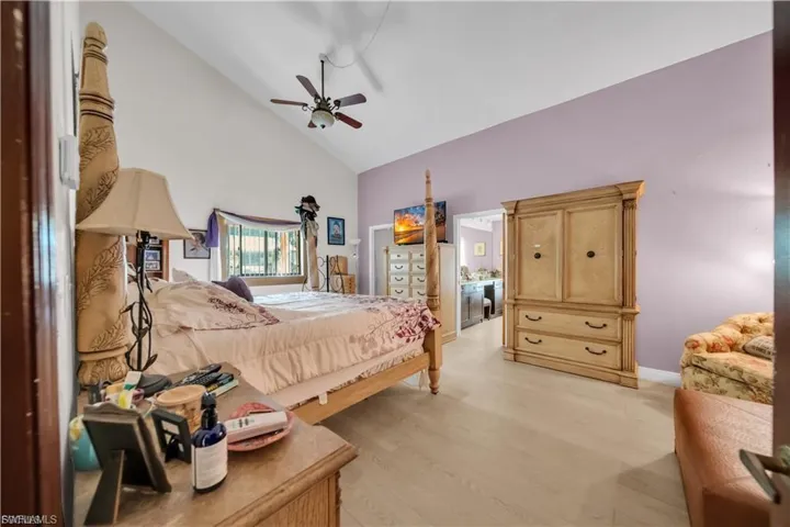 Vaulted ceiling with a ceiling fan, light wood-finish flooring, and a window with horizontal blinds