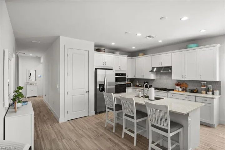 Kitchen featuring tasteful backsplash, visible vents, a sink, appliances with stainless steel finishes, and under cabinet range hood