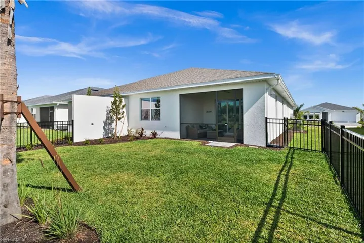 Rear view of property with a lawn, roof with shingles, a fenced backyard, and stucco siding
