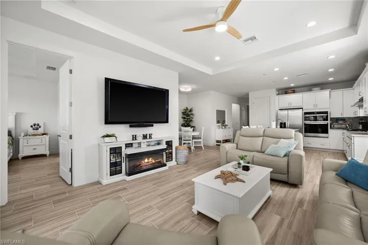 Living room featuring visible vents, a tray ceiling, baseboards, and ceiling fan