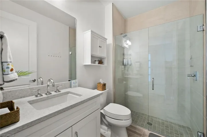 Full bath with a shower stall, vanity, and toilet