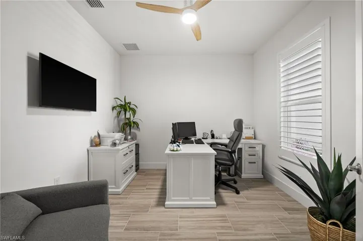 Office area featuring visible vents, ceiling fan, plenty of natural light, and baseboards