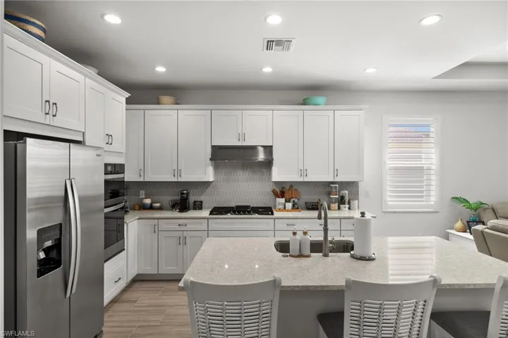 Kitchen featuring recessed lighting, under cabinet range hood, visible vents, appliances with stainless steel finishes, and a sink